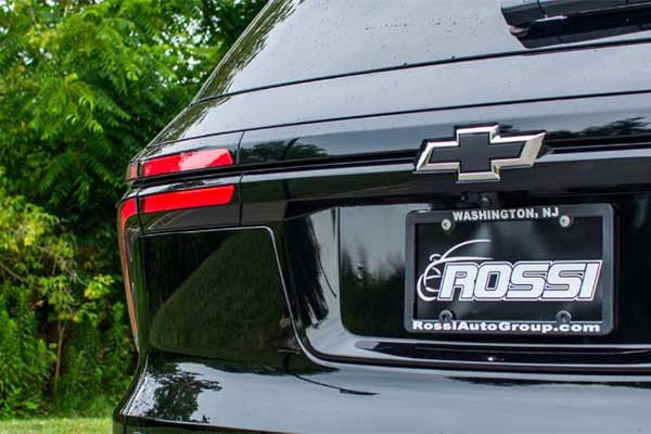 The back Rossi dealership license plate of a black Chevrolet Traverse