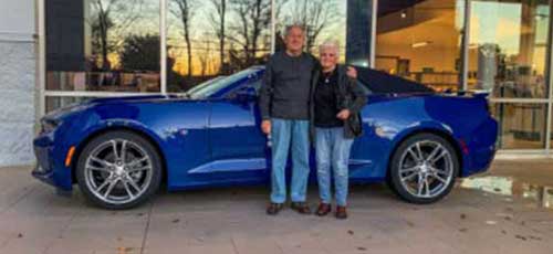 A happy couple who purchased a blue Camaro from Rossi Chevrolet
